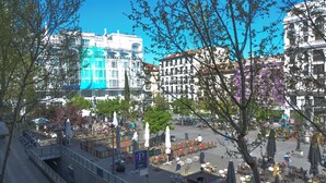A plaza with outdoor seating, a pedestrian bridge, and buildings in the background. - Hotel Miau  (Madrid)