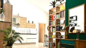 A modern living room with a wooden bookshelf, a large mirror, and a green accent wall. - Rooftop53  (Catania)