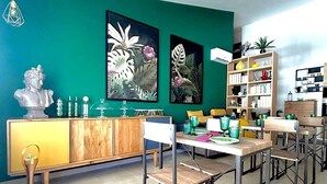 A modern dining area with a teal accent wall, a wooden cabinet, and a metal-framed dining table with chairs. - Rooftop53  (Catania)