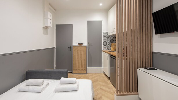 Una habitación de hotel moderna con cama, escritorio, televisor y baño.