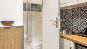 Un baño moderno con cabina de ducha de vidrio, inodoro blanco y lavamanos con salpicadero decorativo.