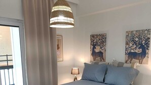 A bedroom with a large bed, a hanging light fixture, and two wall art pieces.