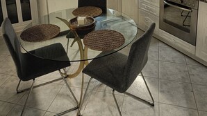 A modern kitchen with a glass dining table, dark chairs, and a built-in oven.
