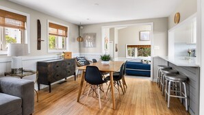 Uma cozinha moderna com mesa de jantar de madeira, cadeiras pretas e um sofá azul.
