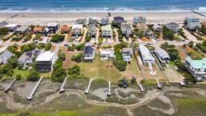 Vista aérea de uma área residencial costeira, com casas, praia e linha de trem.