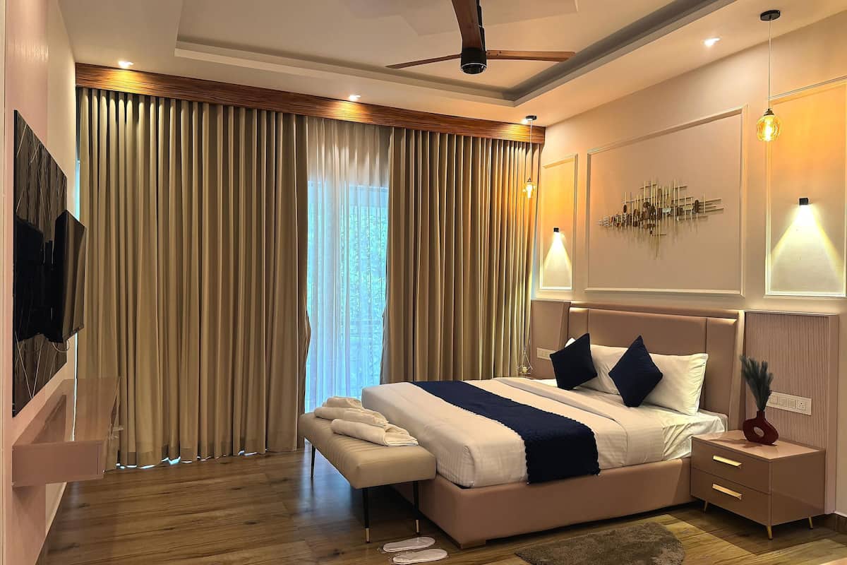 Ein modernes Hotelzimmer mit einem großen Bett, Nachttischen, einem Deckenventilator und Blick ins Freie.