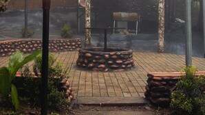 A garden area with a brick pathway, a central fire pit, and a barbecue grill. - Hunters Hideout Resort (Vythiri)