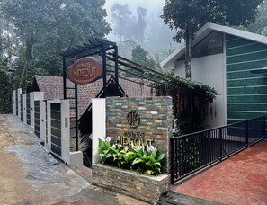 A gated entrance with a stone wall and a sign reading "HUNTERS HIDEOUT". - Hunters Hideout Resort (Vythiri)