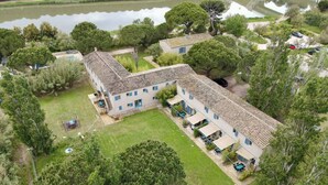 An aerial view of a two-story building with a tiled roof, surrounded by trees and a small pond. - Apartment with pool in the Camargue - family time in a great complex (Saint-Laurent-d'Aigouze)