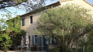 A rustic stone building with a patio area featuring outdoor furniture and a swing. - Apartment with pool in the Camargue - family time in a great complex (Saint-Laurent-d'Aigouze)