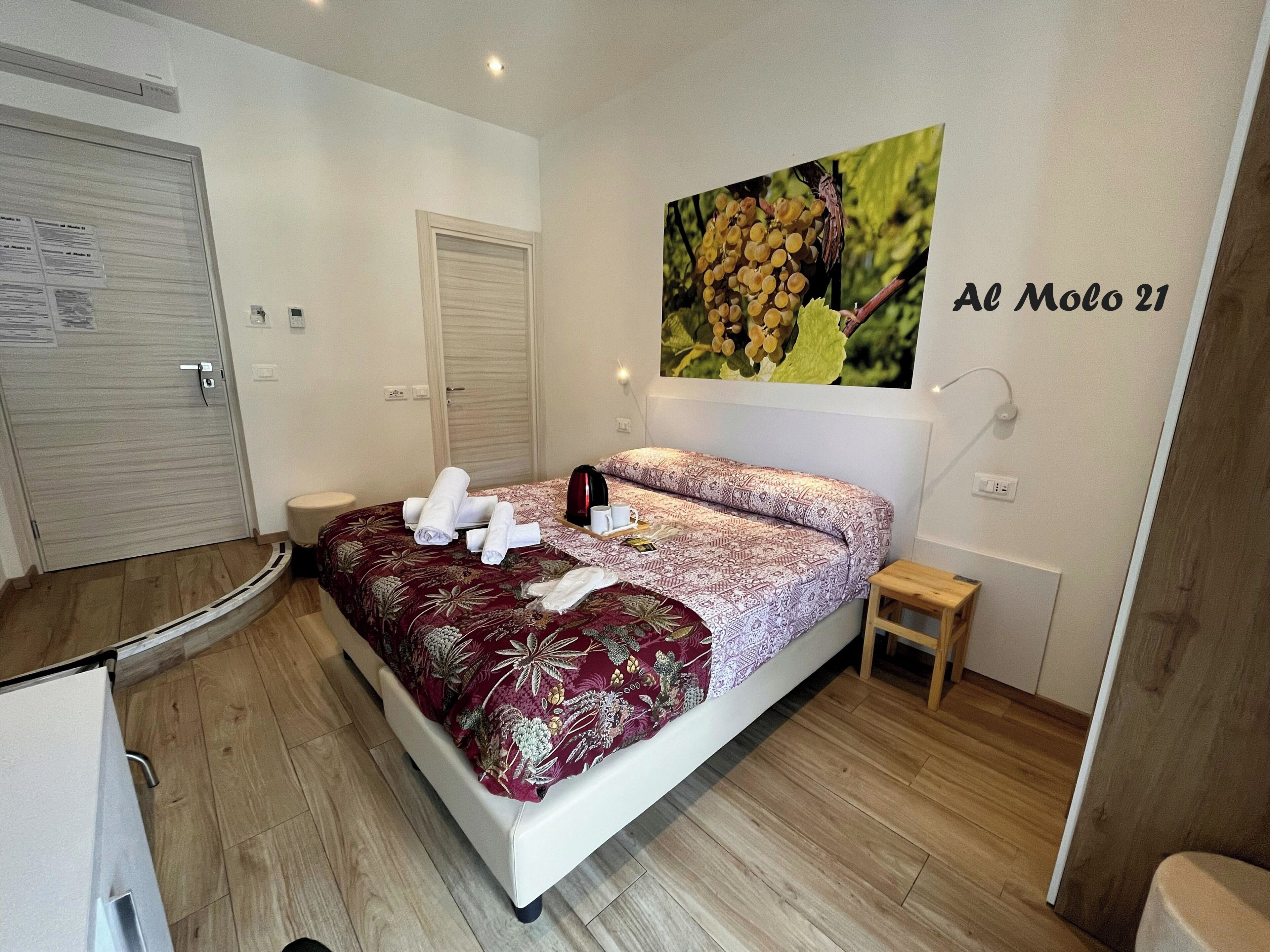 Une chambre d’hôtel avec un lit, une petite table de chevet, un tableau accroché au mur et une porte.