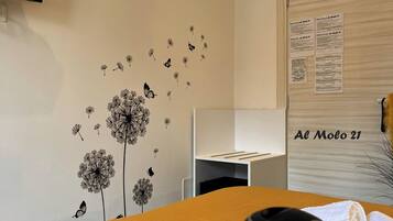 Una habitación con una pared decorada con adhesivos de diente de león y mariposas, una pizarra con texto y un letrero que dice 'Al Molo 21'.