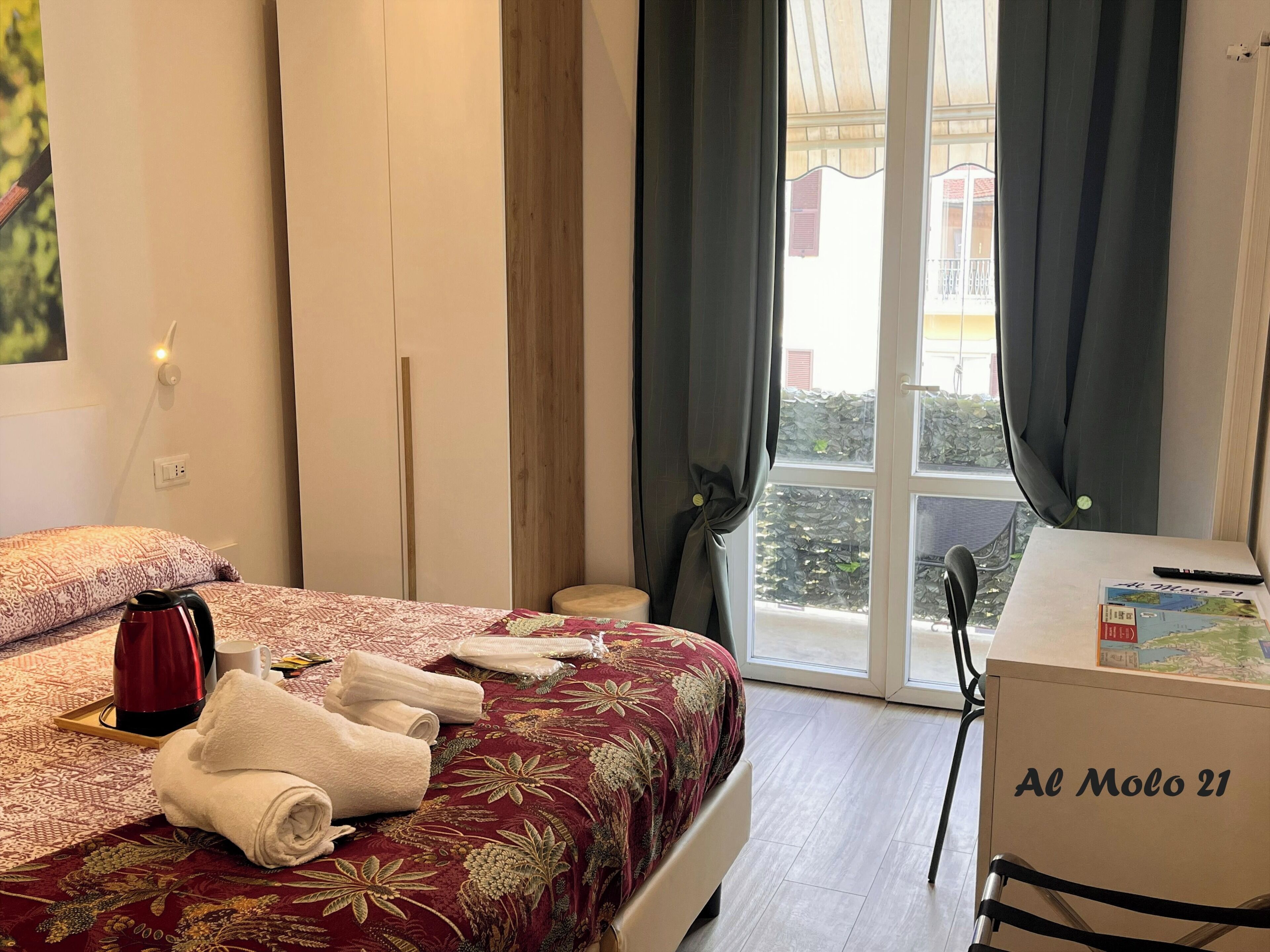Habitación de hotel con cama, escritorio, tetera y toallas.