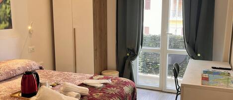 Habitación de hotel con cama, escritorio, tetera y toallas.