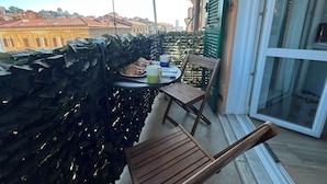 A balcony with a table set for two, a chair, and a view of buildings in the background. - al molo 21 (La Spezia)