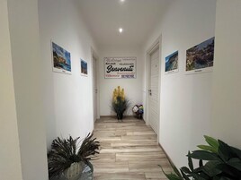 Un pasillo con un cartel de bienvenida, suelo de madera y cuadros en las paredes.