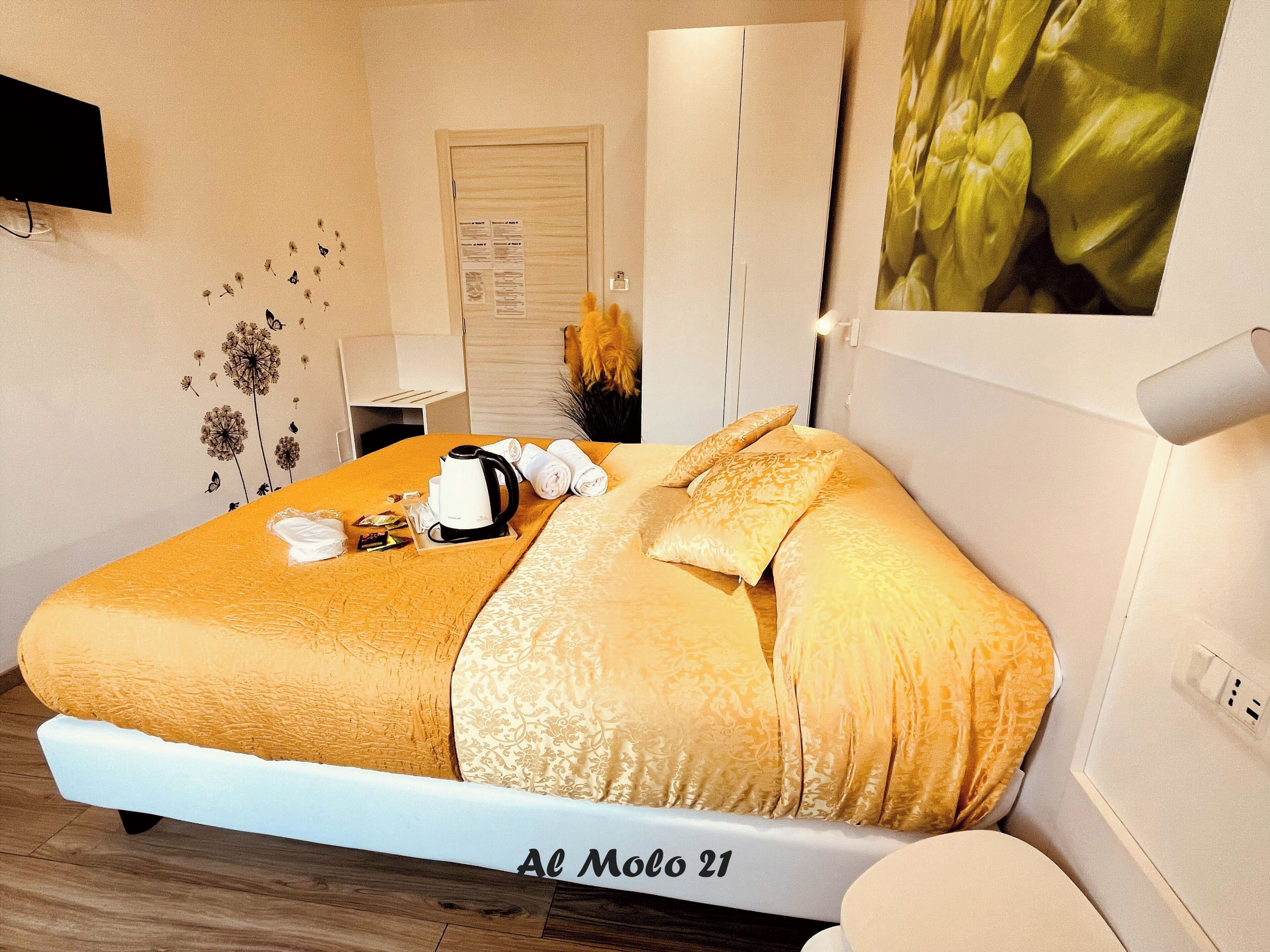 Een hotelkamer met een bed, een nachtkastje met een waterkoker, handdoeken en een dienblad met ontbijtartikelen.