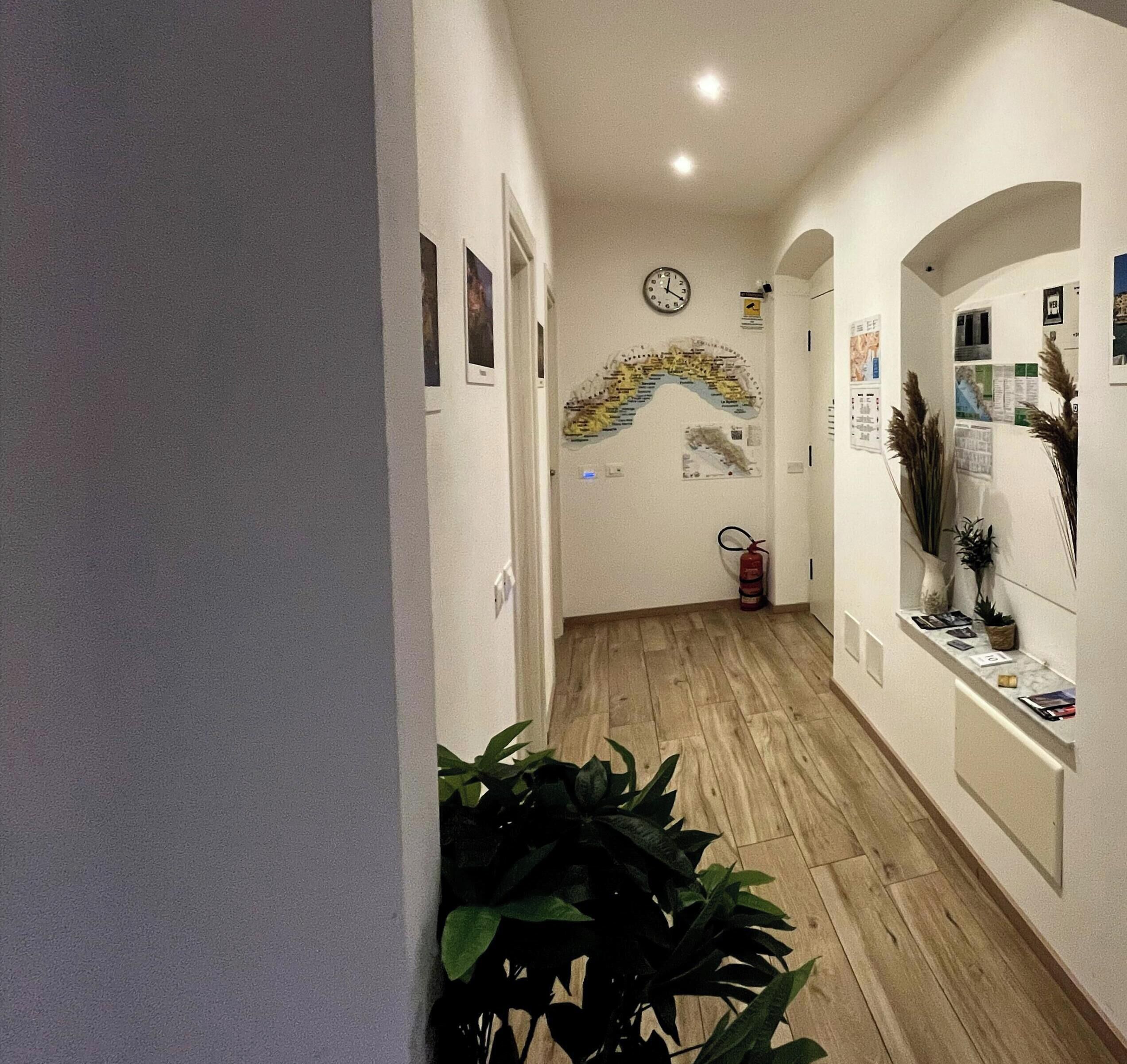 A hallway with wooden flooring, a clock, and wall-mounted decorations.