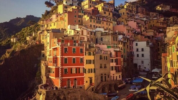A densely packed hillside village with multi-story buildings, narrow streets, and boats docked along the waterfront. - al molo 21 (La Spezia)