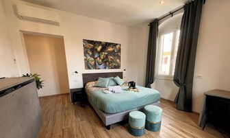 Un dormitorio con cama, mesitas de noche, un escritorio, una ventana con cortinas y un aire acondicionado instalado en la pared.
