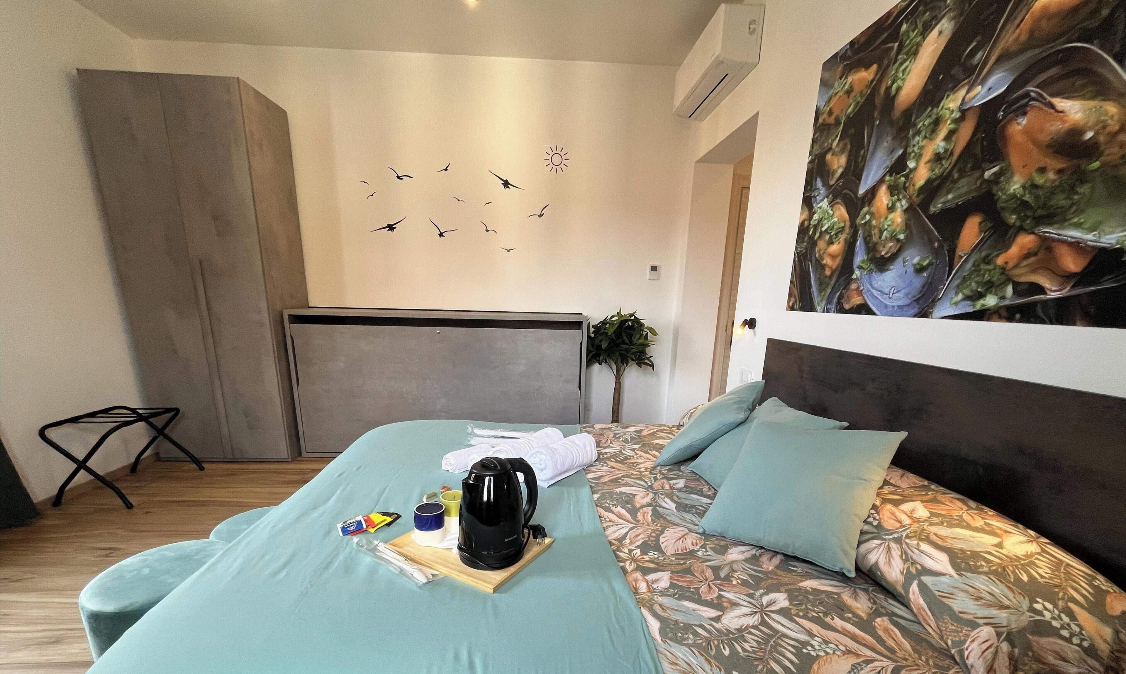 Een kamer met een bed, een schilderij, een plant en een wanddecoratie.