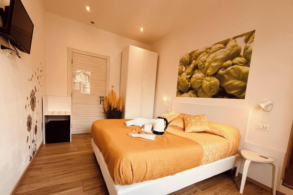 Quarto de hotel com uma cama, televisão, quadro e uma pequena mesa.