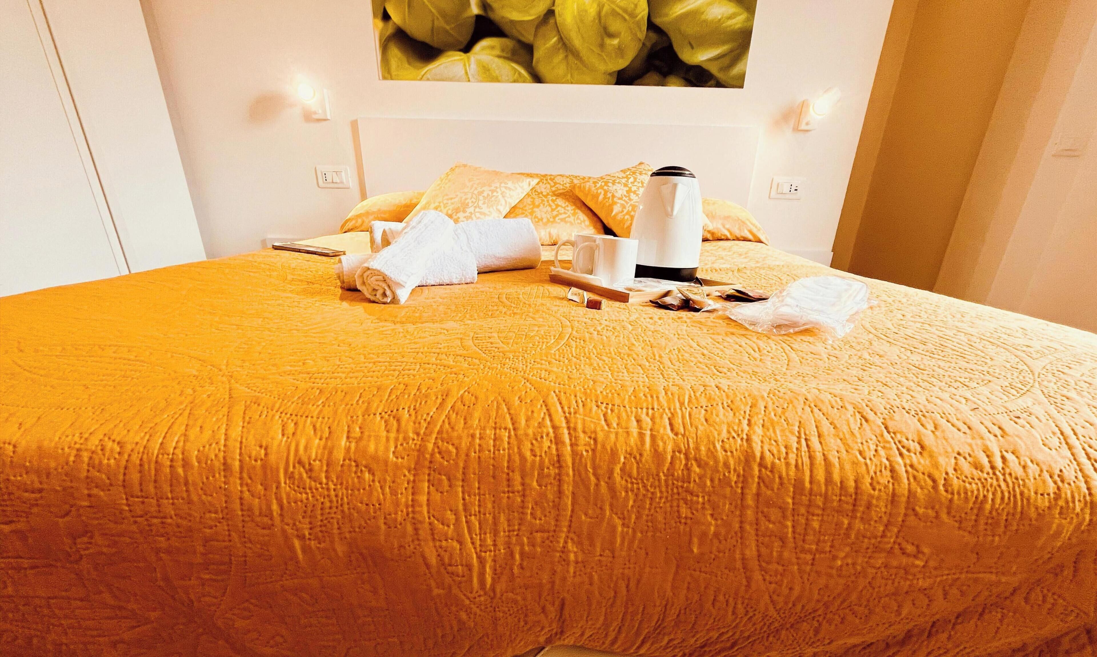 Una habitación de hotel con una cama, una mesita de centro, una taza blanca, otra taza blanca y una toalla blanca.