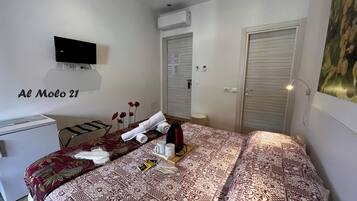 A hotel room with a bed, a desk, a TV, a wardrobe, and a painting on the wall.
