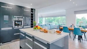 Een moderne keuken met een groot eiland, inbouwapparatuur en een eethoek met uitzicht.