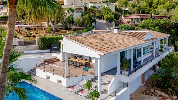 Een moderne villa met een zwembad, terras en uitzicht op het omliggende landschap.