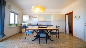 A modern kitchen with white cabinets, a central island, and a hanging light fixture. - Solemar Sicilia - Casa Bella (Bagheria)