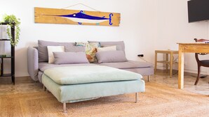 A modern bedroom with a sofa bed, a wooden side table, a small desk, and a wall-mounted TV. - Solemar Sicilia - Casa Bella (Bagheria)