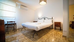 A bedroom with a bed, a desk, a chair, a bedside table, and a hanging light fixture. - Solemar Sicilia - Casa Bella (Bagheria)