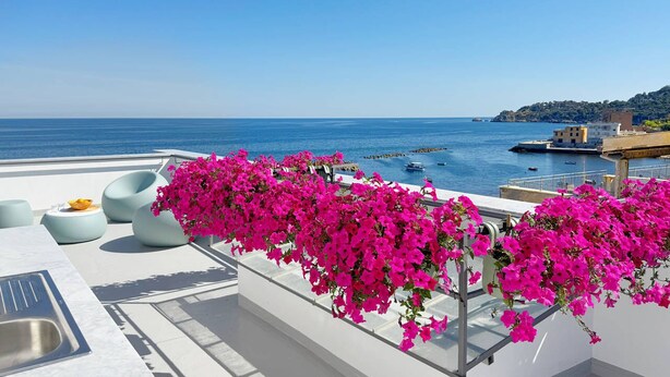 A terrace with a view of the sea, featuring a white outdoor seating area and pink flowers. - Solemar Sicilia - Casa Bella (Bagheria)