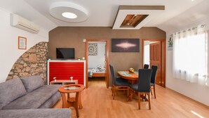Un salon moderne comprenant un canapé, une table à manger avec des chaises, un téléviseur et une cheminée.