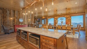 Une cuisine spacieuse avec des meubles en bois, un grand îlot central et des luminaires suspendus.