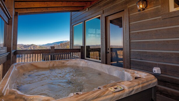 Un bain à remous sur une terrasse en bois, avec vue sur les montagnes.