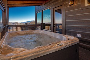 Un bain à remous sur une terrasse en bois, avec vue sur les montagnes.