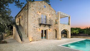 A stone building with a pool, a balcony, and a staircase.