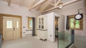 A spacious room with a high ceiling, a glass railing, and a white cabinet with glass doors.