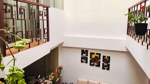Un espace de vie spacieux, aménagé sur plusieurs niveaux, avec un ensemble de canapés, des œuvres d’art décoratives et des plantes en pot.