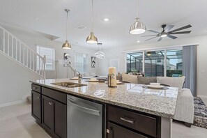 A modern kitchen with granite countertops, stainless steel appliances, pendant lighting, and a ceiling fan. - 5BR Pool Townhome Near Disney • Gameroom (Clermont)