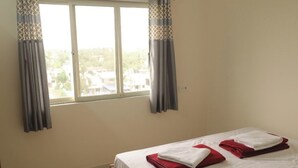 A bedroom with a bed, a ceiling fan, an air conditioning unit, and a window with curtains. - Antique Homestay Daman (Daman)