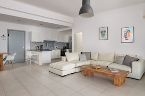 Una sala de estar moderna con un sofá, una mesa de centro y una cocina al fondo.