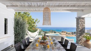 A dining table set with breakfast items and a view of the ocean. - Modern Luxury Villa in Vlicha (4347+W3Q Lindos, Greece)