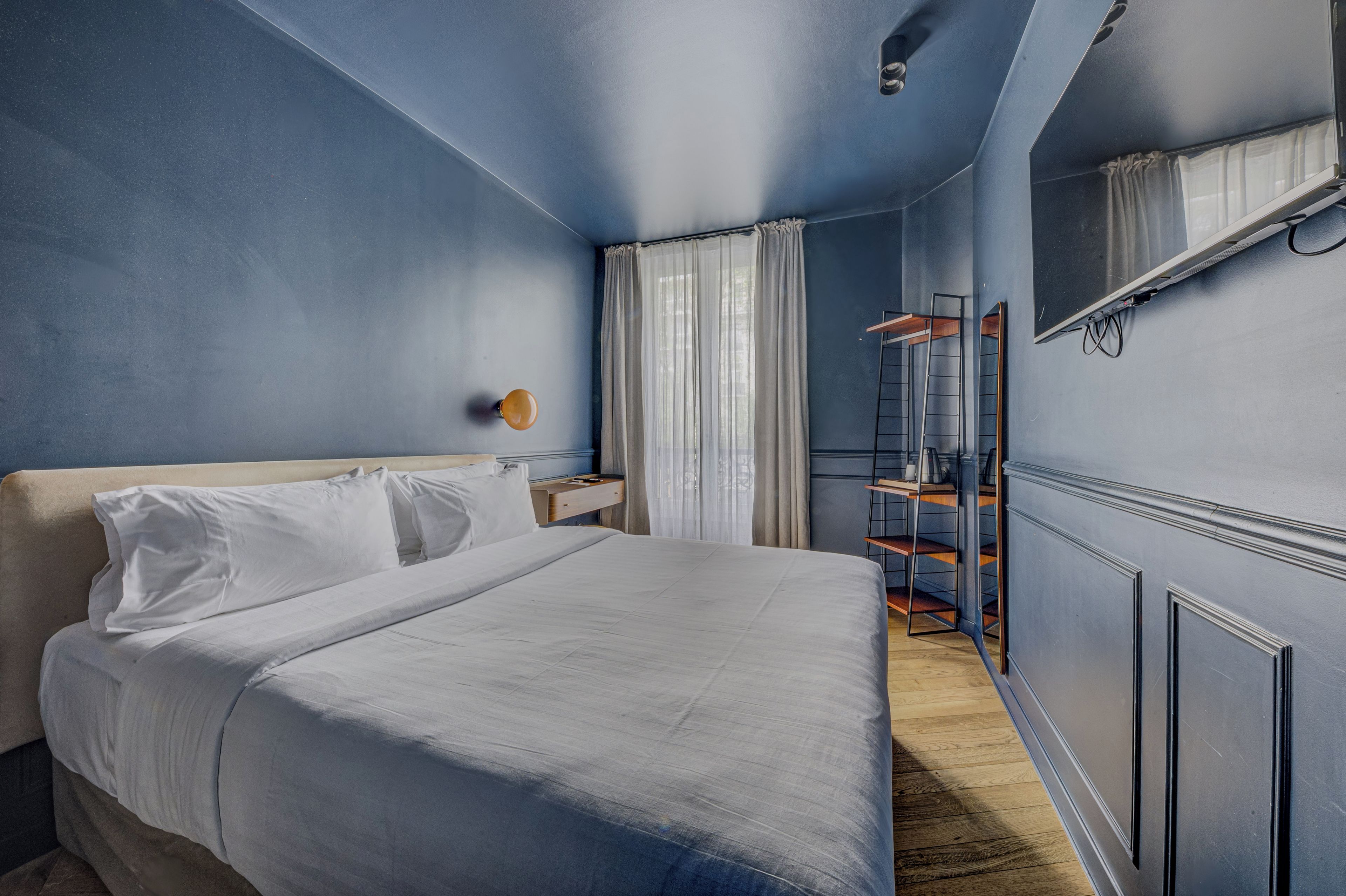 Une chambre à coucher avec un lit, une table de chevet, un miroir et une armoire.