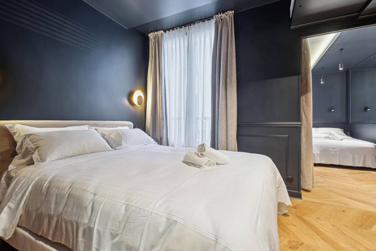 Een moderne slaapkamer met een groot bed, een spiegel en een houten vloer.