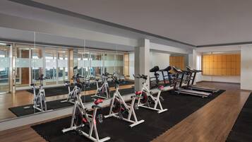 Un gimnasio con bicicletas estáticas, cintas de correr y equipo de ejercicio.