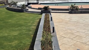 A landscaped outdoor area with a pool, seating areas, and a view of the ocean. - Ginger Diu Jalandhar Beach (Diu)