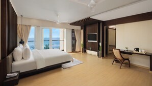 A modern hotel room with a large bed, a desk, and a view of the ocean. - Ginger Diu Jalandhar Beach (Diu)